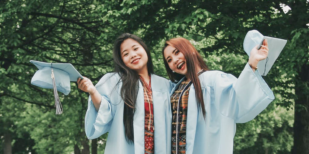 2 new female college graduates in cap and gowns