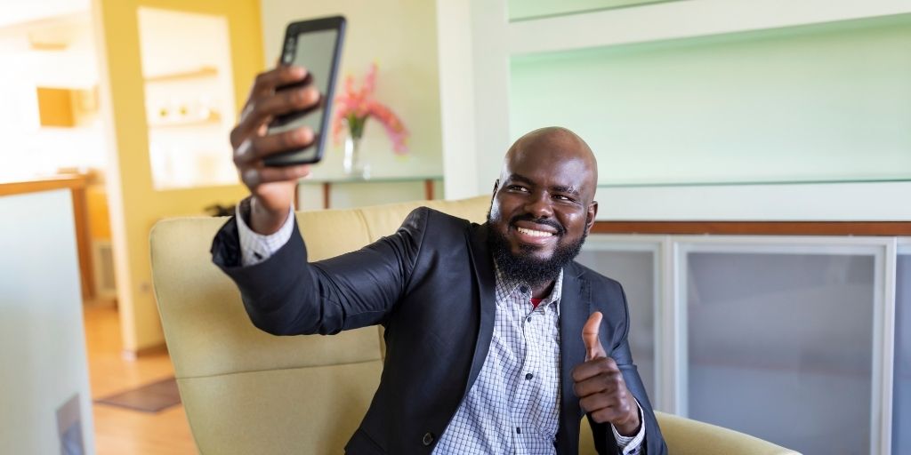 man taking a selfie while displaying a thumbs up in show of self confidence