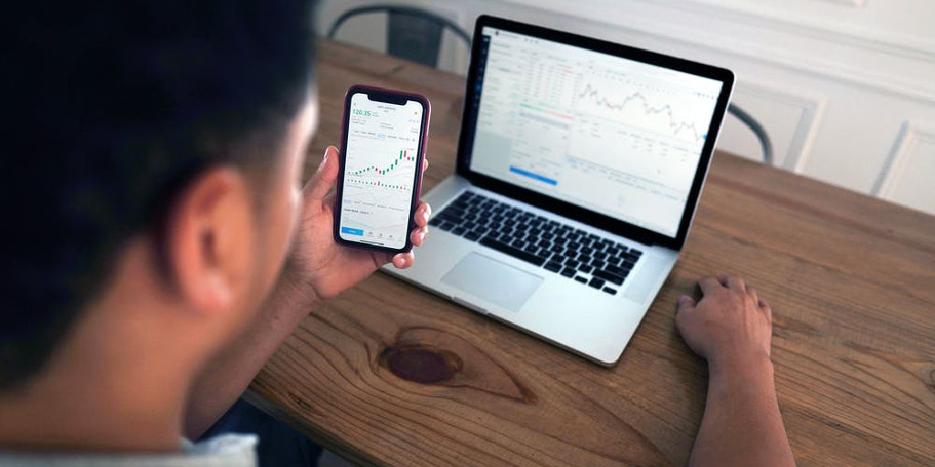 investor viewing stock portfolio on smartphone and computer