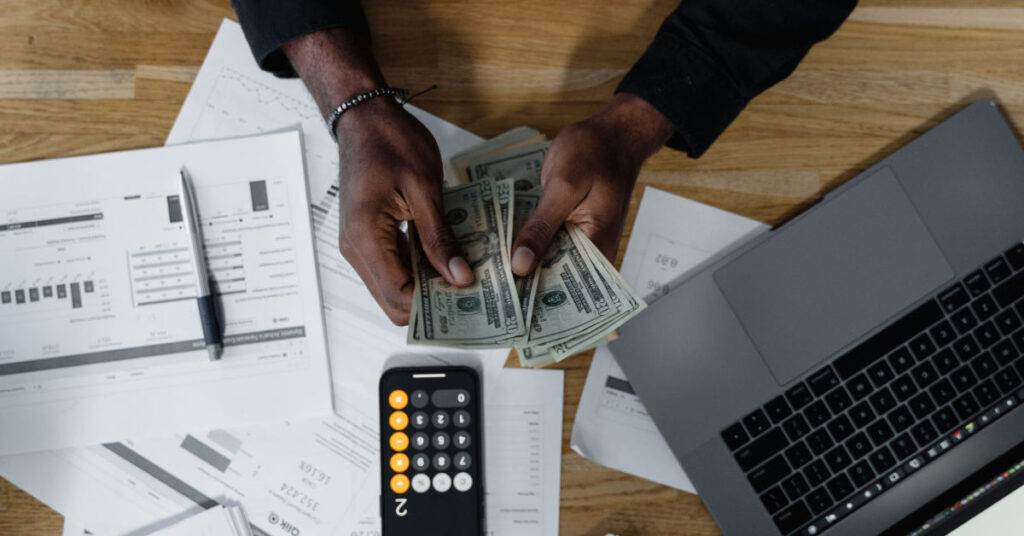overhead view of man counting cash to invest