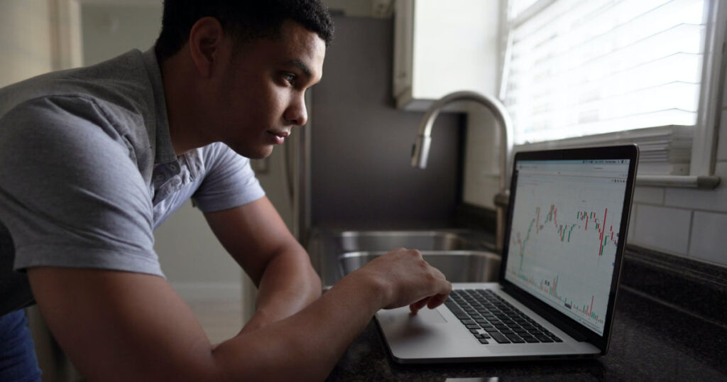 young man looking at investing charts on laptop