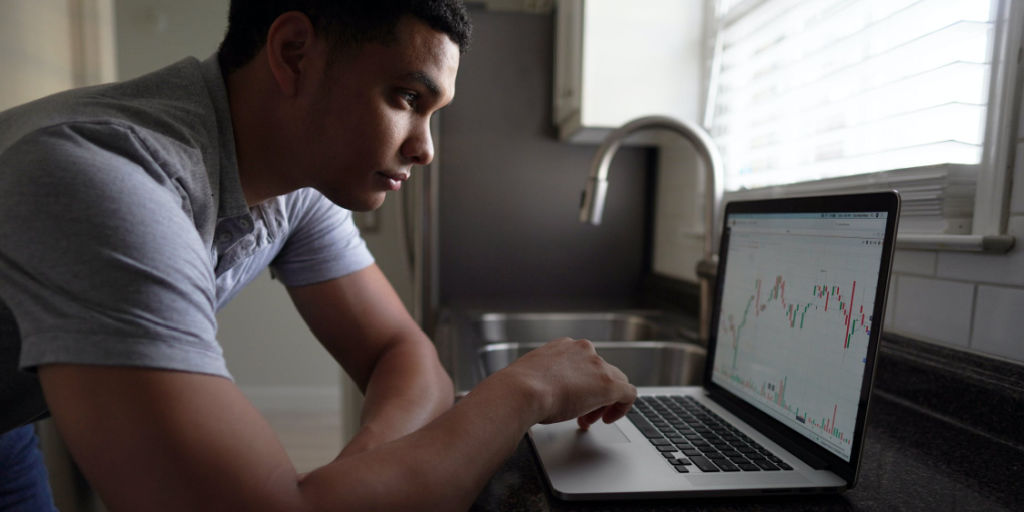 young man looking at stock market charts on laptop