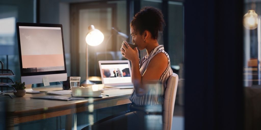 female sitting at computer drinking tea and contemplating starting a side hustle