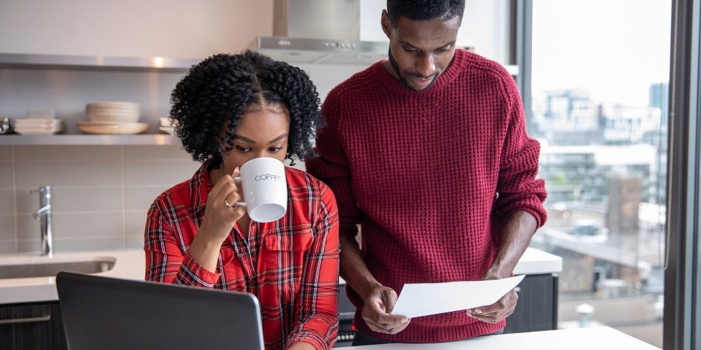 african american couple reviewing finances in kitchen while drinking coffee in kitchen